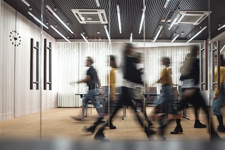 A blurred image of people walking in an office.